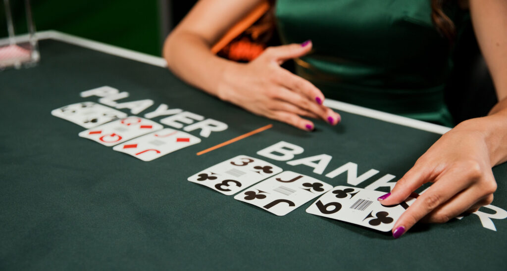 Woman playing baccarat with cards on a green table, focusing on game strategy.